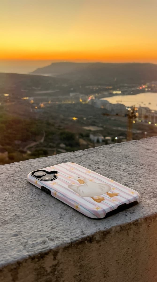 Duck-pattern Avellé case resting on a wall at sunset over Gozo
